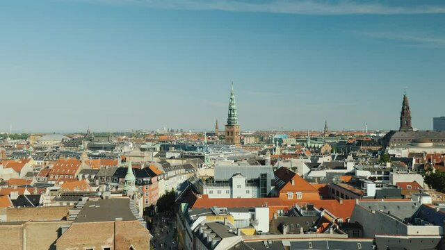 The city of Copenhagen, an old city often with old-tiled roofs and spiers. Pan shot