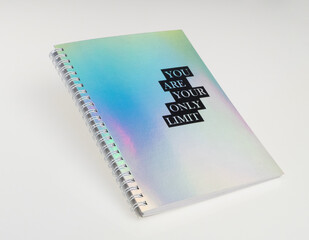 a notebook with iridiscent cover and motivational text, white background