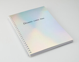 a notebook with iridiscent cover and motivational text, white background