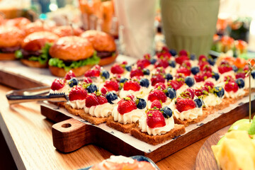 Desserts and burgers on table, toned