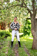 A stylish young girl with a shovel fashionably poses on a Sunny summer day in the backyard garden.