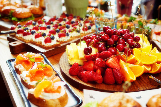 Fruits, fish snacks and dessert on catering table, toned