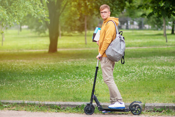 Handsome guy, man, young college or university student or pupil in glasses riding on electric urban...