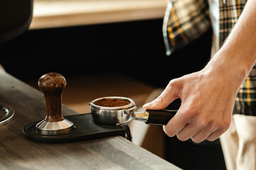 Fototapeta na wymiar Barista presses ground coffee using tamper. Professional barista working makeing coffee with coffee machine. Hot pouring drink concept. Toned picture