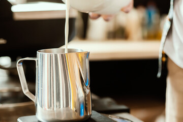 Barista pours milk into a stainless steel milk jug. Latte art for barista. Coffee Accessories. Barista Kit.