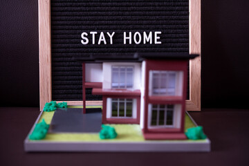white text stay home on black felt letter board and house model
