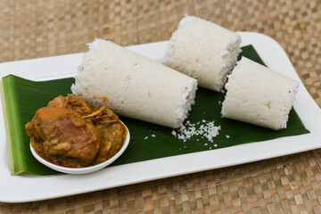 Popular South Indian breakfast puttu / pittu made of white rice flour and coconut in a bamboo mould, with banana, Kerala, India. Bamboo puttu prepared in the bamboo utensil. 