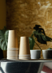 Still unused paper coffee cups and ceramic espresso cups are on the coffee machine.