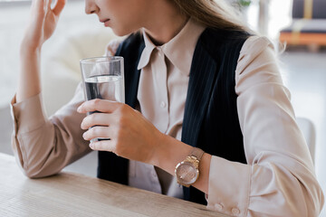 cropped view of businesswoman holding glass of water