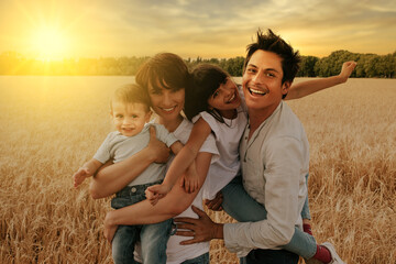 portrait of a happy and smiling family in a wheat field under a sunset