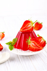 Sweet dessert jelly pudding with strawberries on white plate
