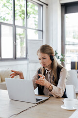 selective focus of attractive operator in headset gesturing while talking near laptop and cup