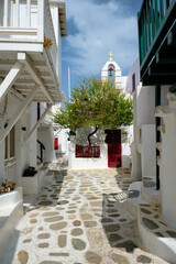 Picturesque scenic narrow Greek streets with traditional whitewashed houses with blue doors windows of Mykonos town and orthodox church in famous tourist attraction Mykonos island, Greece