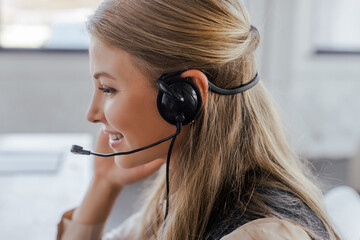 side view of cheerful operator in headset smiling in office