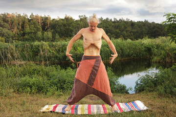 Handsome fit man doing yoga at the park