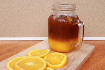 Orange slice and orange juice in a glass place on a wooden chopping block.