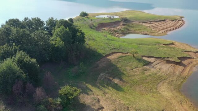 Rama Lake in Bosnia and Herzegovina over island with eroded shore and trees, Aerial flyover shot