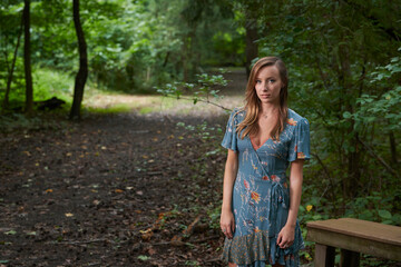 Stunning young Caucasian woman posing outside near trail in woods - summer themed in print wrap dress