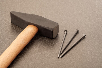 three nails and a large hammer on a ceramic surface