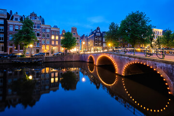 Fototapeta na wymiar Night view of Amterdam cityscape with canal, bridge and medieval houses in the evening twilight illuminated. Amsterdam, Netherlands