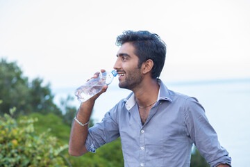 Hydrate yourself. Man smiling in profile about to drink from a b