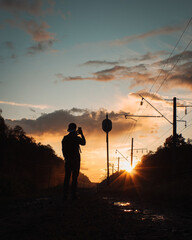 Silhouette of a man standing with phone against the sunset