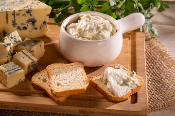 Blue cheese cream and toasted bread on wood background. Pate de gorgonzola in Brazil.