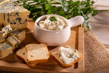 Blue cheese cream and toasted bread on wood background. Pate de gorgonzola in Brazil.