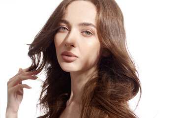 Beautiful young brunette with natural make-up and silk long hair on a white background. Shadow on the face. Woman looking at camera. Isolated over white background.