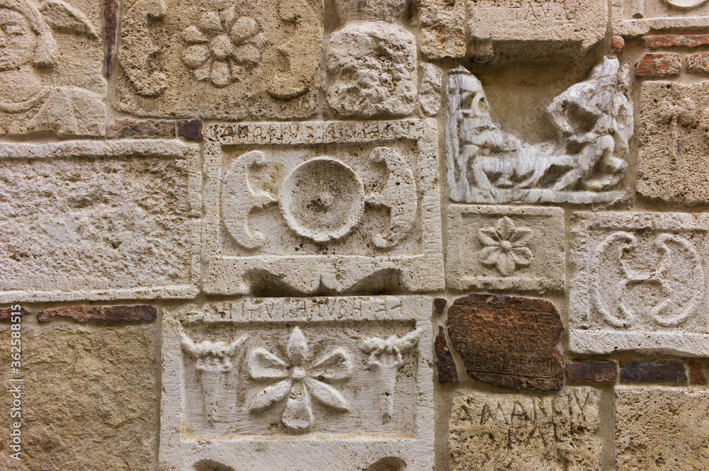 Wall mural etruscan and roman stone carving reliefs on a wall of palazzo bucelli in montepulciano, tuscany, ita