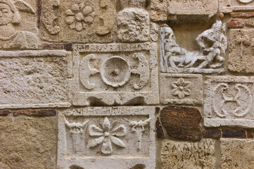 Etruscan and Roman stone carving reliefs on a wall of Palazzo Bucelli in Montepulciano, Tuscany, Italy