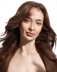 Beautiful young brunette with natural make-up and silk long hair on a white background. Shadow on the face. Woman looking at camera. Isolated over white background.