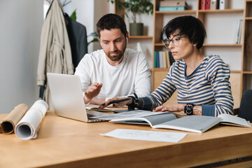Photo of young colleges discussing project while working in office