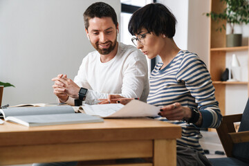 Photo of young colleges discussing project while working in office