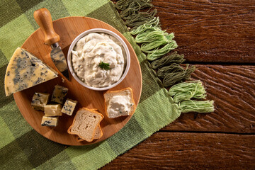 Blue cheese cream and toasted bread on wood background. Pate de gorgonzola in Brazil.