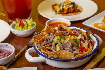 Preparation authentic Mexican nachos on wooden table.