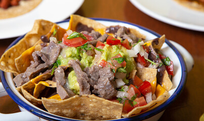 Close up of nachos with guacamole and beef steak