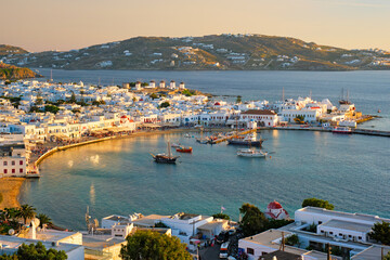 Fototapeta na wymiar View of Mykonos town Greek tourist holiday vacation destination with famous windmills, and port with boats and yachtson sunset . Mykonos, Cyclades islands, Greece. With horizontal camera panning