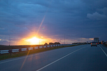 transport rides on the highway in the evening at sunset. Road and cars away