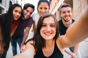 Group of best friends taking a selfie with smartphone in the city - Millennial having fun in summer together - Portrait of people in the street in a moment of break and relax