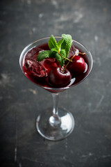 Cherry cocktail in martini glass with berries and mint leaves. Selective focus. Shallow depth of field.
