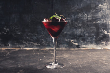 Cherry cocktail in martini glass with berries and mint leaves. Selective focus. Shallow depth of field.
