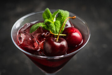 Cherry cocktail in martini glass with berries and mint leaves. Selective focus. Shallow depth of field.
