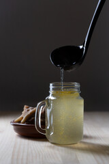 Homemade Beef Bone Broth in Glass Storage Jar on a black background