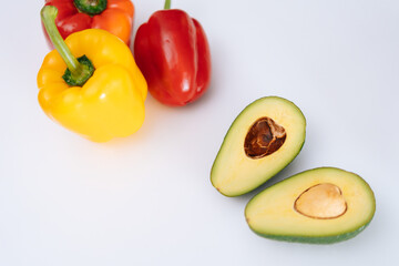 Sliced avocado and bell peppers on white background, top view . Fresh vegetables and fruit on white table. Concept of healthy eating.