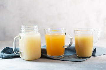 Three types of Homemade Beef Bone Broth in Glasses on a gray background