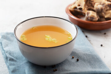 Homemade Beef Bone Broth in a bowl on a gray concrete background with meat