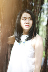Fototapeta premium Beautiful asian woman in white dress relax and smiling in natural park. Thai girl or Chinese Girl enjoy on holiday with sunlight in garden