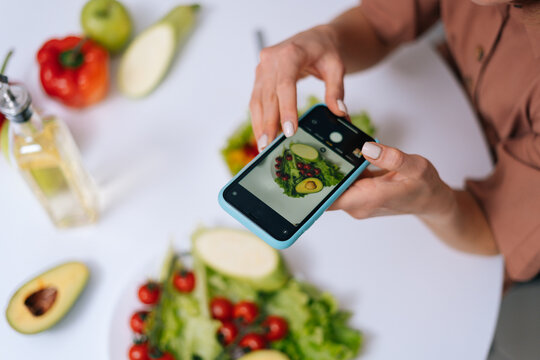 Close-up view of woman making photos vegetable salad with camera of cellphone to place pictures at social media resources. Concept of healthy eating.