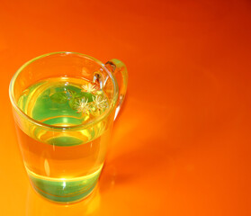 Lime tea with lime flowers on a bright orange background.